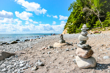 Stacked stones (Cairns) at the pebble beach with chalk cliffs at Piratenschlucht (