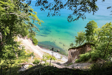 Turquoise waters of the Baltic sea and white cliffs framed in trees seen from Hochuferweg hiking path at Wissower Ufer, Jasmund National Park, Rügen, Mecklenburg-Vorpommern, Germany. 