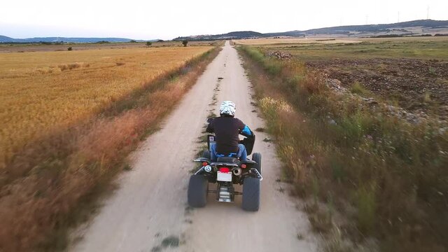 Riding quad bike. Man in protective equipment and helmet, drifting on his ATV at sunset. Aerial footage. High quality 4k footage