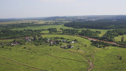 Fototapeta na wymiar Aerial view russian village on bank of river spring or summer green landscape houses top view on suburb. During the coronavirus lockdown. Forest near village. Top view from drone.