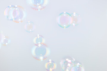 Beautiful rainbow soap bubbles float on white background.