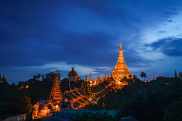 The golden Shwedagon Pagoda during blue hour twilight with dramatic sky cloud