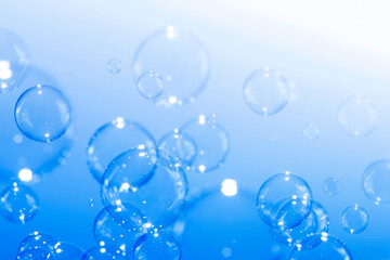 Closeup beautiful clear soap bubbles float on blue background.
