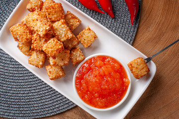 .Squares of tapioca and cheese served with pepper jelly. Wooden table. Space for text - Dice of tapioca. Top view