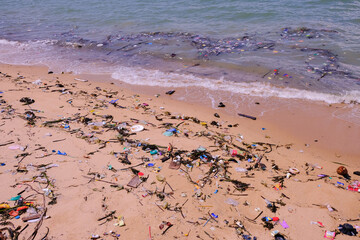 Beach pollution. Trash (plastics, bottles, other waste garbage) from the tropical sea washing ashore. Selective focus. Environmental concept. Worse during covid-19