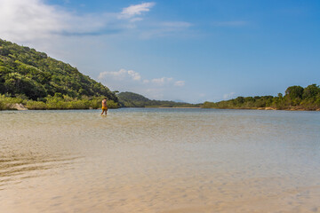 Homem atravessando um rio em pé. Linda paisagem do rio Itaguaré, reserva ambiental, cercada pela...