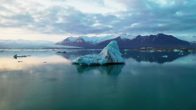 Iceberg Floating On A Calm Lake At Sunrise In Jokusarlon Glacial Lake In South Island - Drone Orbiting Shot