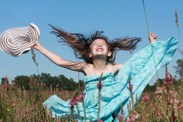 Excited happy girl enjoying outdoor activity, having fun and going crazy on flowery meadow, making...