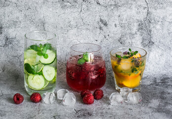 Variety of lemonade on a gray background. Lemonade with raspberries, peach, fresh thyme and refreshing water with lime, cucumber and mint