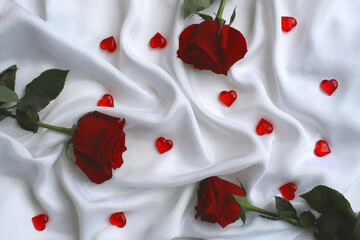 Three roses lie on a white satin fabric