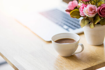 a cup of coffee and laptop on wood floor with flower, vintage style