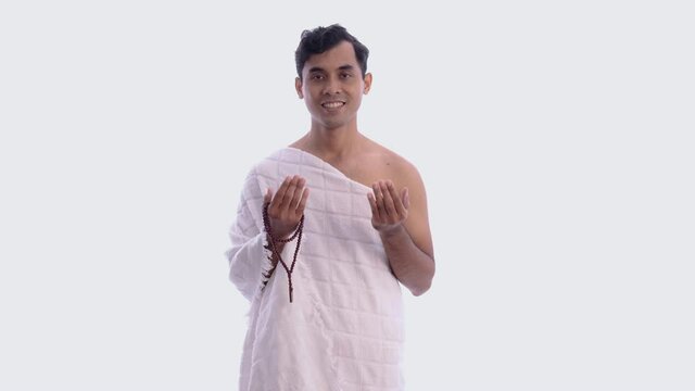 Muslim man praying wearing ihram isolated over white background
