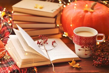 Autumn books.Autumn cozy  reading. Books and  cup of tea, a checkered scarf,  orange pumpkin, red berries and garland on a wooden table..NaNoWriMo Writing Autumn Marathon.Fall time