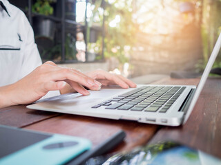 close up of hands typing on laptop in cafe.