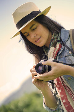 Portrait of dark-haired woman with hat taking pictures with vintage camera