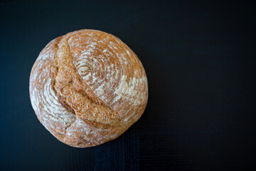 Fresh wheat homemade bread on the black background. Daylight, indoor, copy space