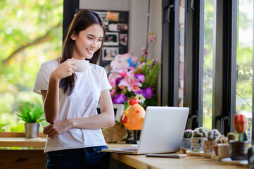 Asian woman or a happy student smiles on a desk with a computer.