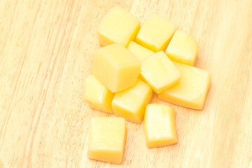 Close Up of Mozzarella Cheese Cubes on Wooden Plate Isolated on White Background