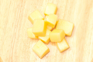 Close Up of Mozzarella Cheese Cubes on Wooden Plate Isolated on White Background