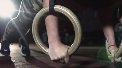 Naklejka premium Muscular woman is doing push-ups on gymnastics rings