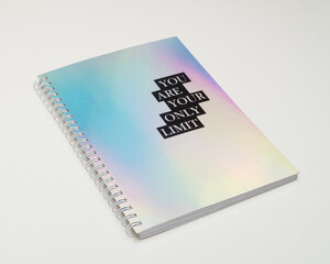 a notebook with iridiscent cover and motivational text, white background