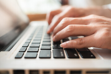 Close up hands of woman using laptop computer working and searching online information with blurry background. copy space of technology business and social distancing concept