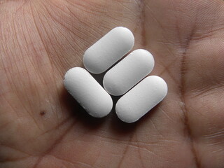 Fototapeta na wymiar Small oblong shape white medicine pills on palm of hand