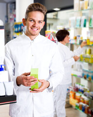 Fototapeta na wymiar Portrait of handsome man druggist in white coat giving advice to customers in pharmacy