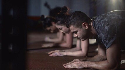 Fototapeta na wymiar Young sporty attractive people doing plank exercise on mat at crossfit gym.