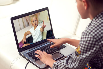 Fototapeta na wymiar The boy communicates using a webcam on a laptop while sitting at home . Friends communicate via video conferencing