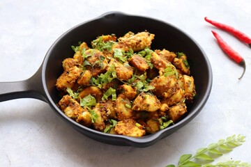 Stir fried taro roots. Arbi ki sabji, Taro roots masala curry. Arbi Masala. Garnished with coriander, red chili & curry leaves. copy space.