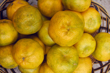 yellow ripe tangerines in a basket, green tones