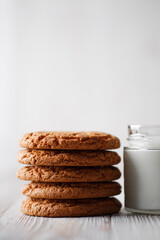 Tasty cookies and a glass of milk in a transparent glass on a rustic white background. Copy space