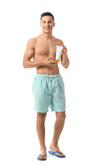 Fototapeta premium Happy young man with sun protection cream on white background