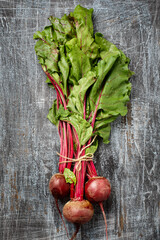 Bundle of fresh organic farmer young beetroots with haulm on dark scratched background, top view