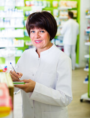 smiling woman wearing uniform and working in pharmaceutical shop