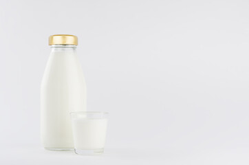 Milk, white dairy product in glass bottle  mock up with glass on soft light white background, copy space.