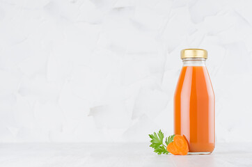 Fresh vegetable orange carrot juice in glass bottle template with green parsley, slices on wood table and white background with copy space.
