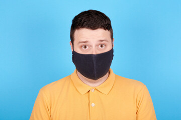 Angry brunette man in protection mask screaming, rage and mad expression. Isolated on blue background.