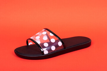 Rubber flip flop with dot pattern. Isolated on red background.