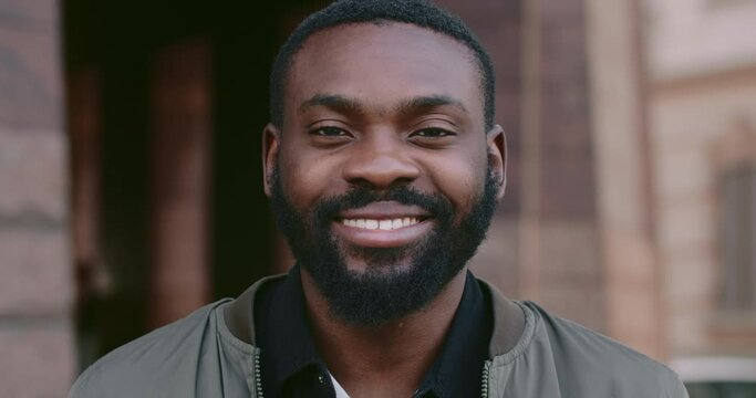 Facial portrait of young afro american man smiling while looking to camera. Close up of handsome bearded man with happy facial expression. Concept of emotions. Blurred background