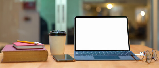 Study table with books, mock up tablet with keyboard, smartphone, glasses and paper cup