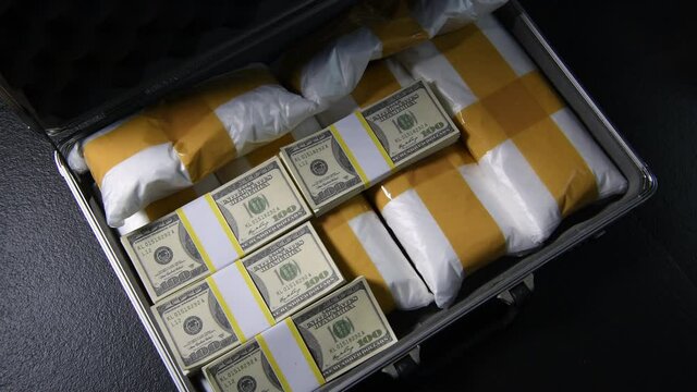 A hand packing narcotic drugs and money in briefcase .