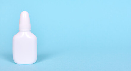 Nasal spray, drops in white bottle. Isolated on blue background, copy space template, banner.