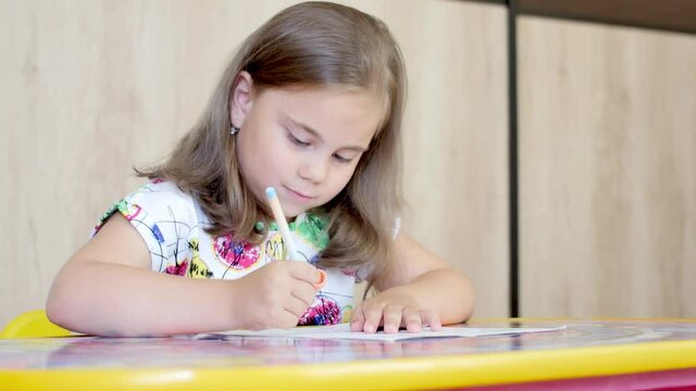 Happy little girl or cute primary child school child painting or writening on paper. Children elementary education concept.