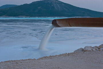 Industrial wastewater is discharged from pipe into the water