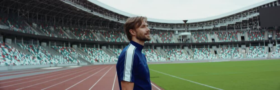 Young adult Caucasian male sportsman soccer player entering and admiring a large empty stadium. Shot on RED Cinema camera