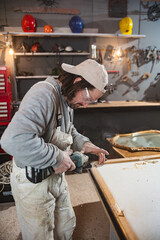 Male carpenter working on old wood in a retro vintage workshop.