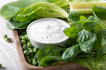 greek yogurt with green vegetables on a wooden tray