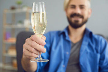 Crop man sitting in chair with glass of champagne